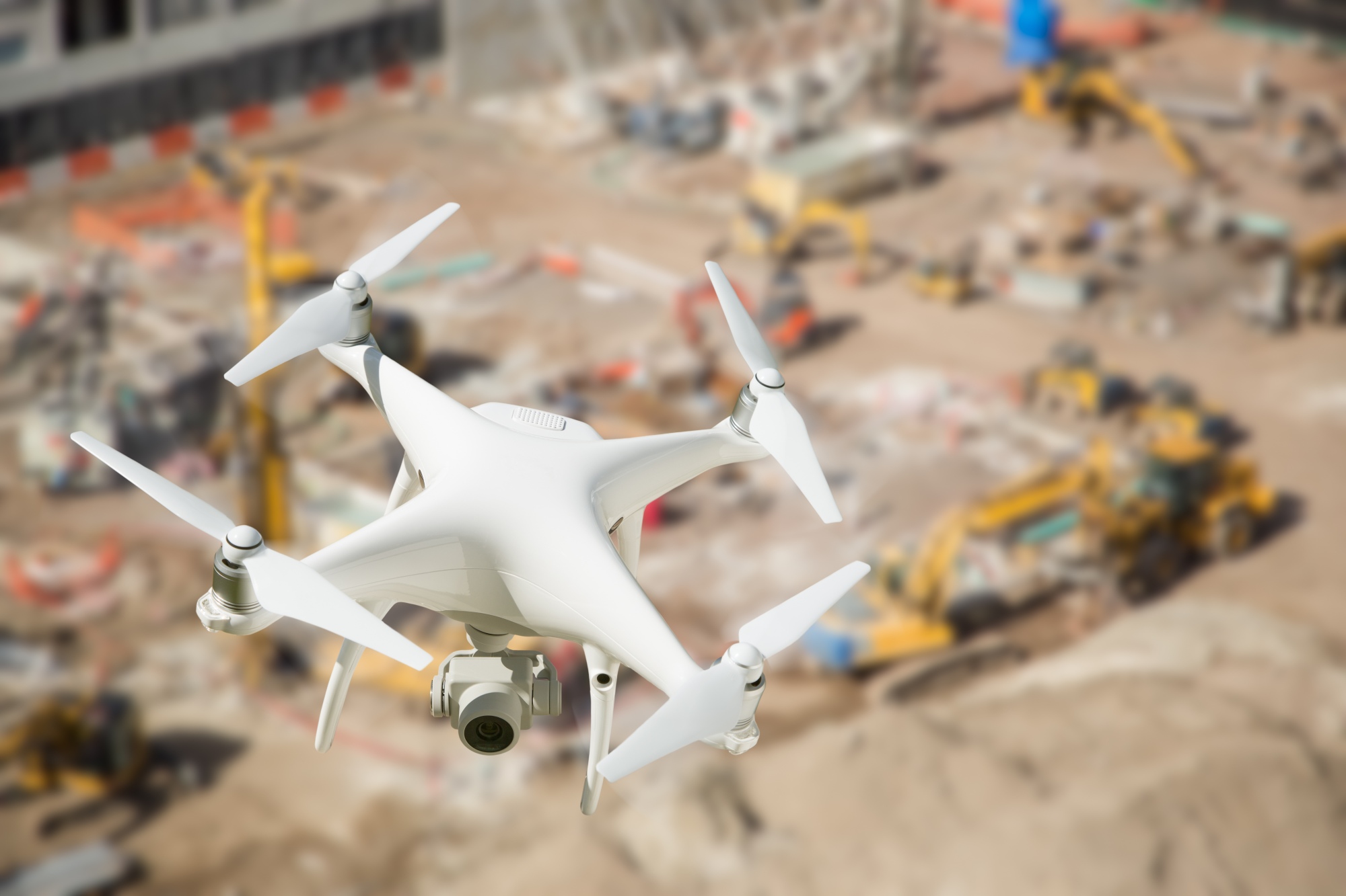 Unmanned Aircraft System (UAV) Quadcopter Drone In The Air Over Construction Site