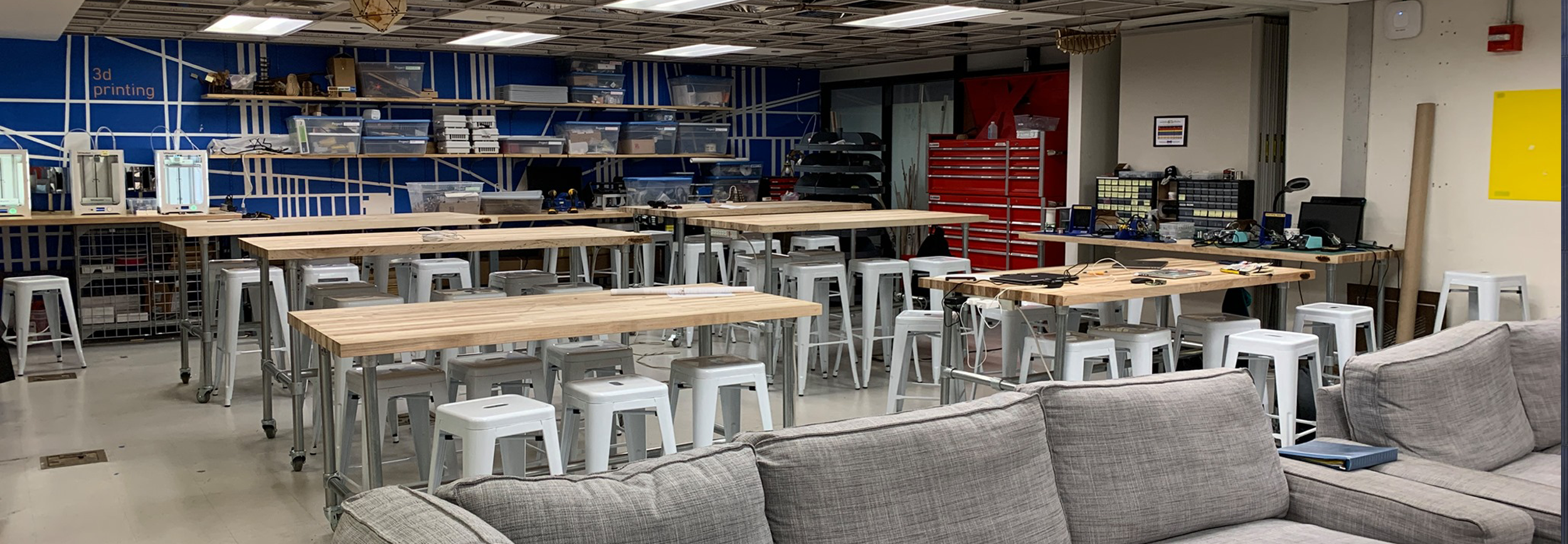 A makerspace with work desks, equipment shelves and couch space
