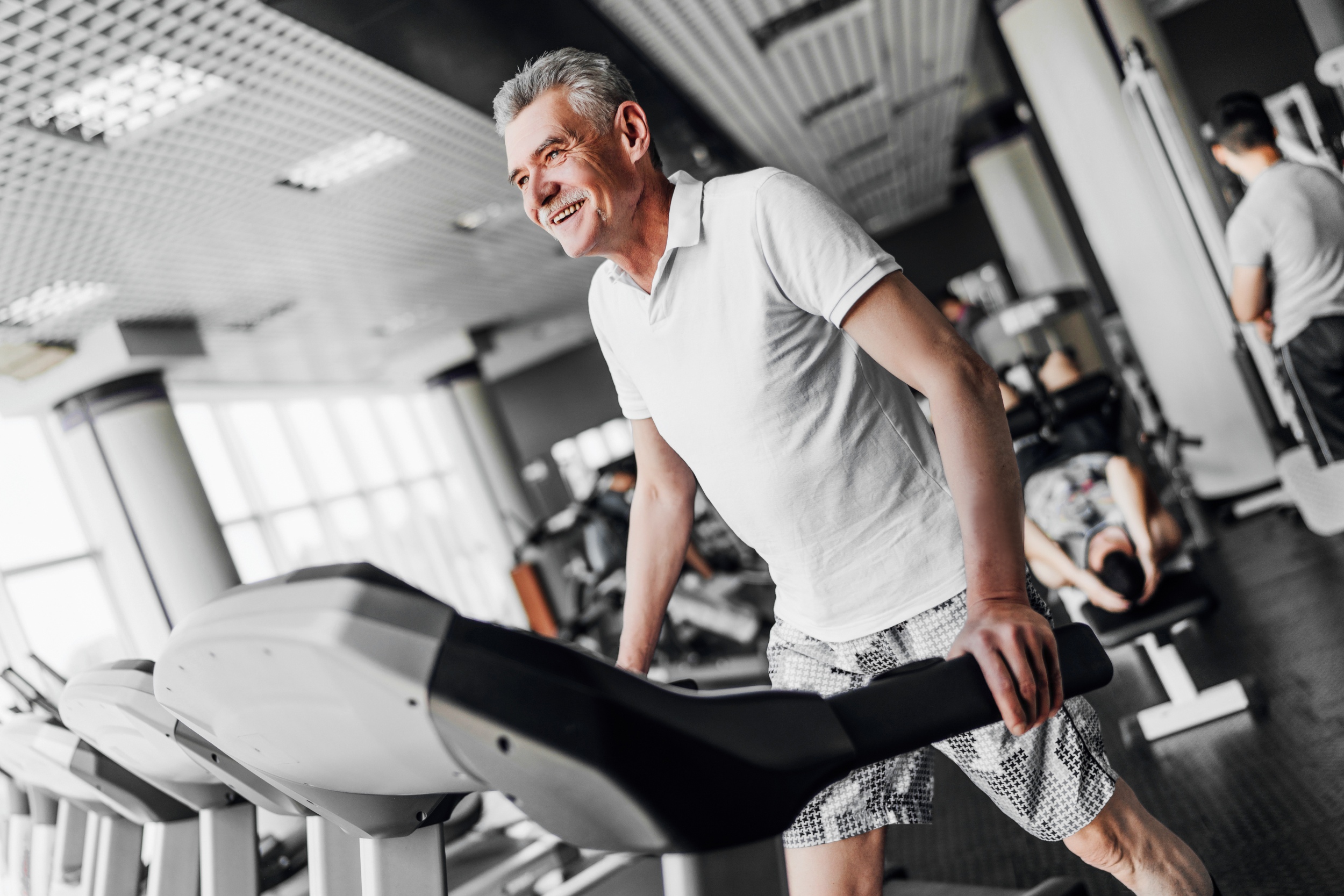 Older man smiles and walks on treadmill