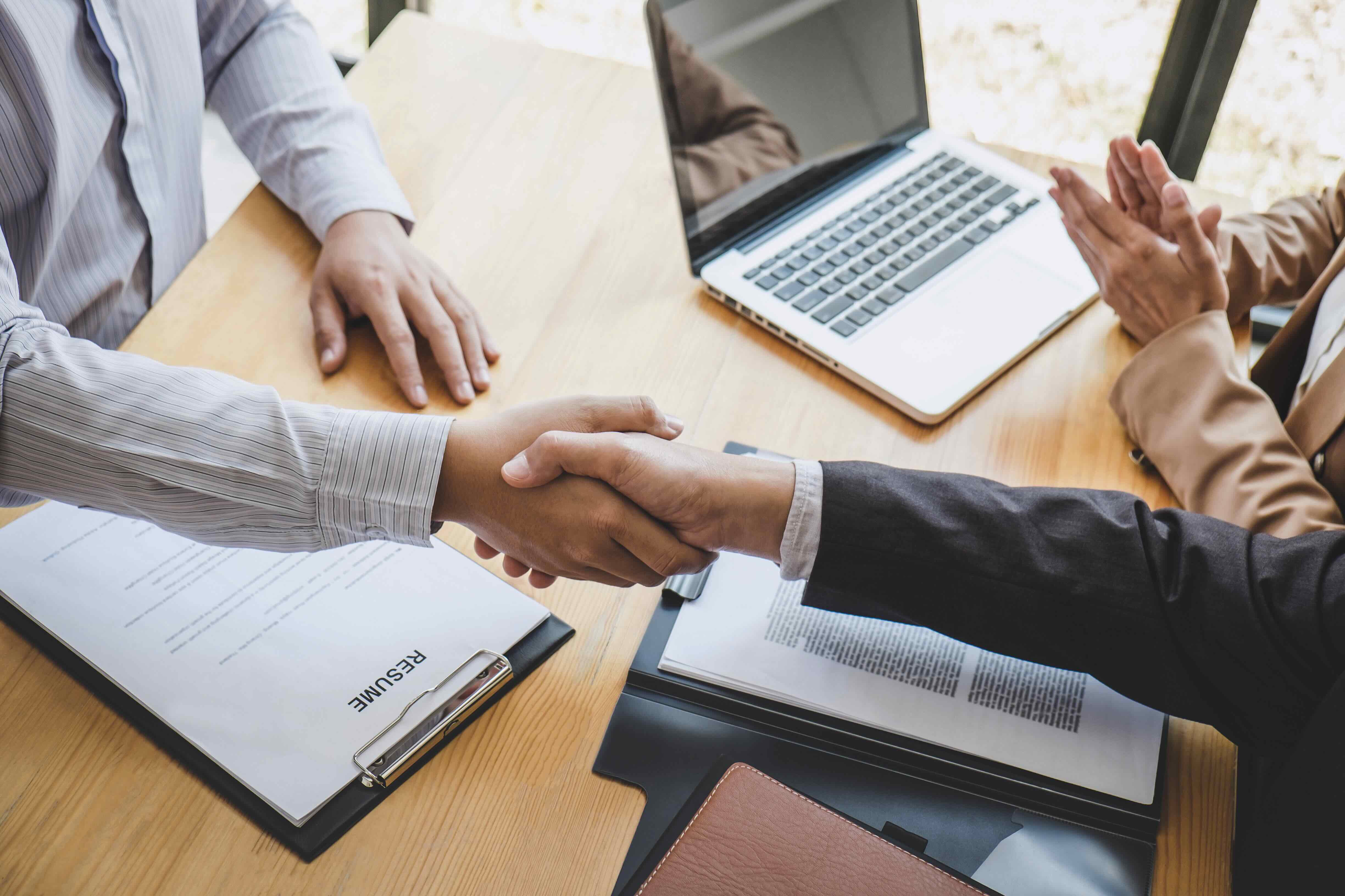 A handshake shows greeting new colleagues, Handshake while job interviewing, male candidate shaking hands with Interviewer or employer after a job interview, employment and recruitment concept.