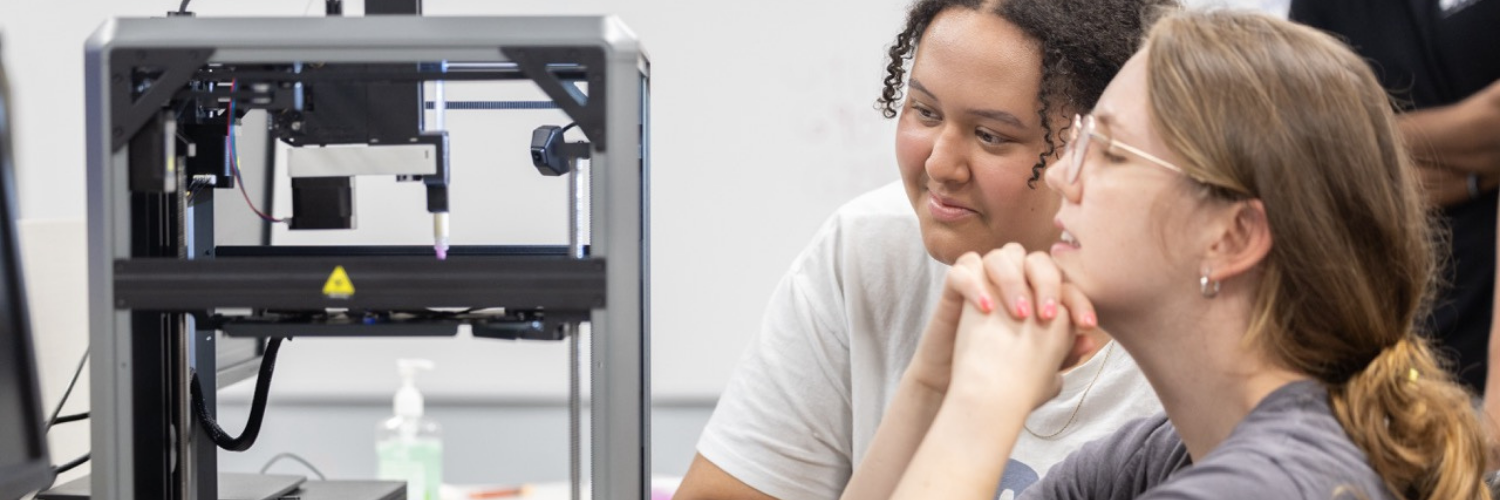 a CampBioE 2.0 scholar and counselor peer into a 3D Bioprinter