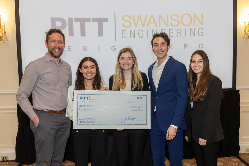 Four students standing with Professor Steiner holding a check for winning the spring 2024 design expo