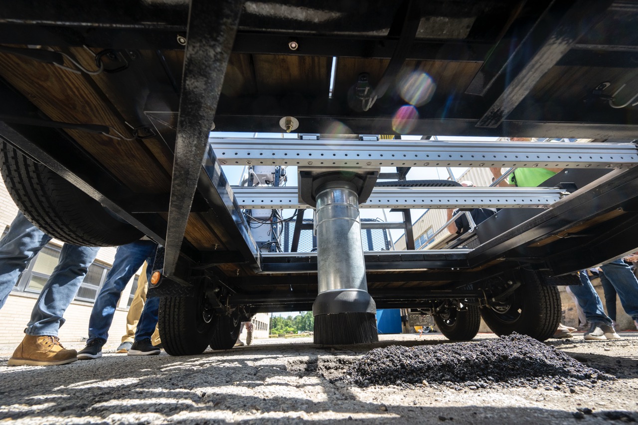 Silly Surfacing prototype in action seen from ground level as asphalt fills a pothole