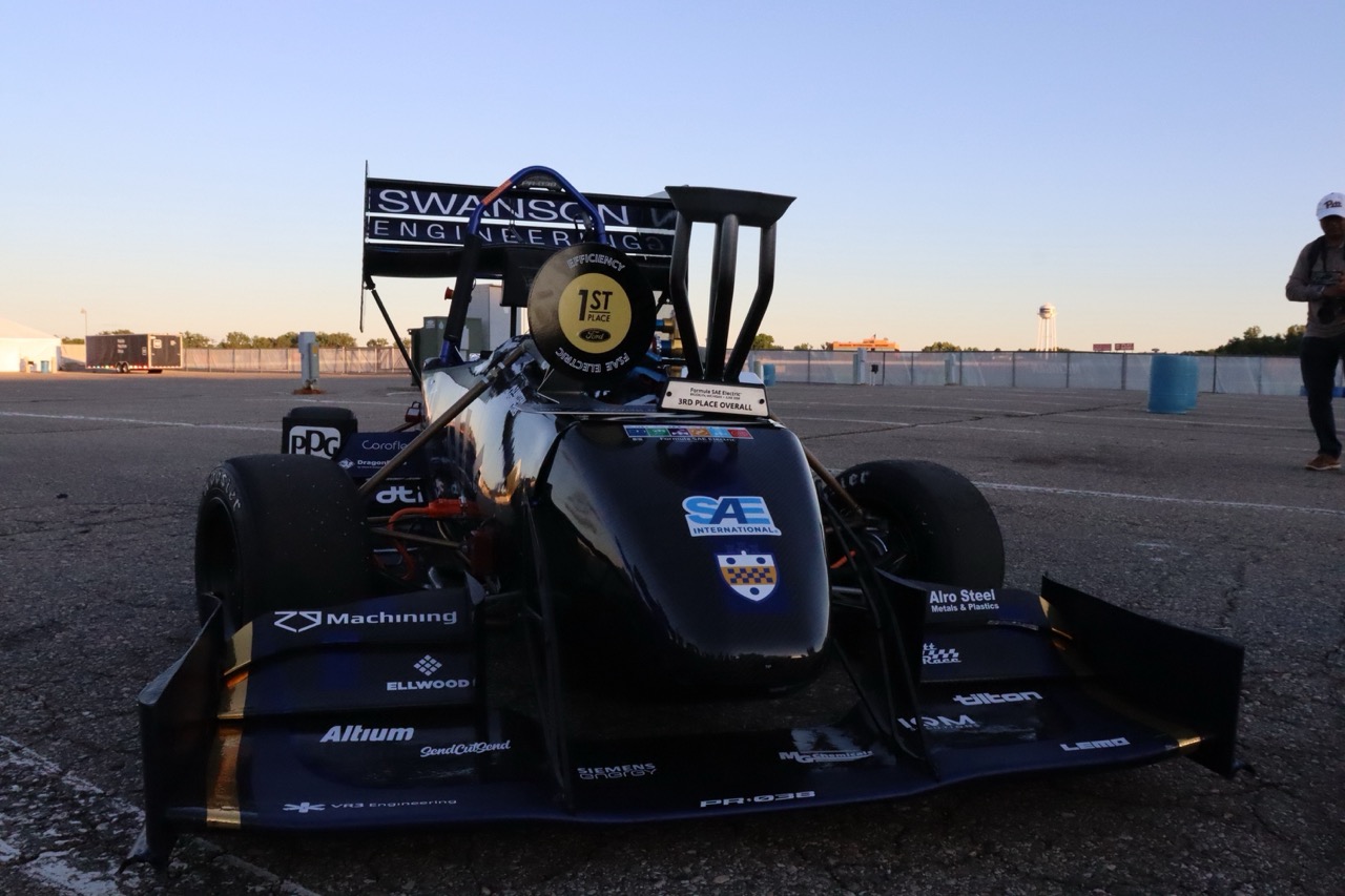 Panther Racing FSAE car on the tarmac in Michigan up close, with a trophy on it.
