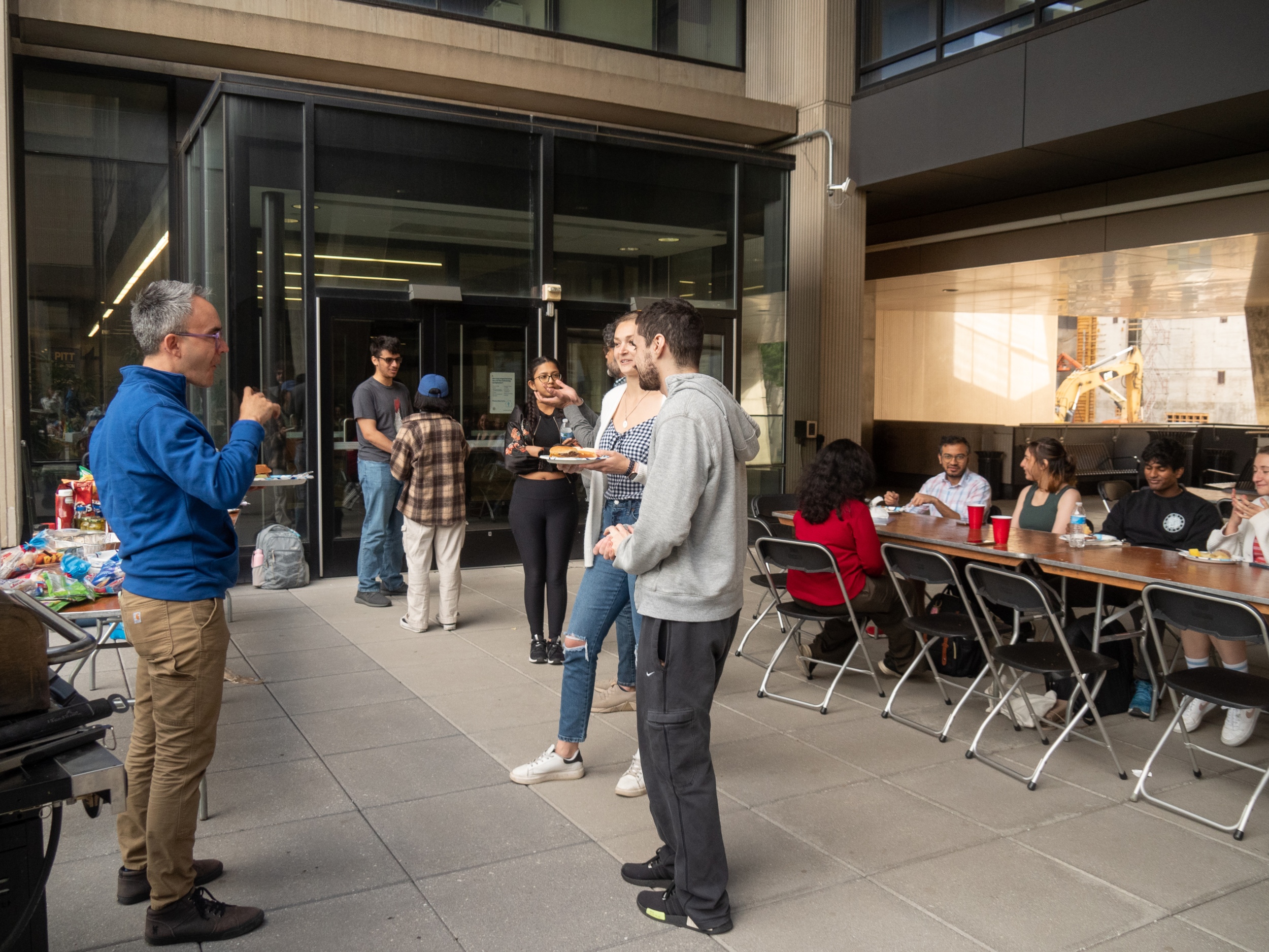 Students at bbq event talking to a professor