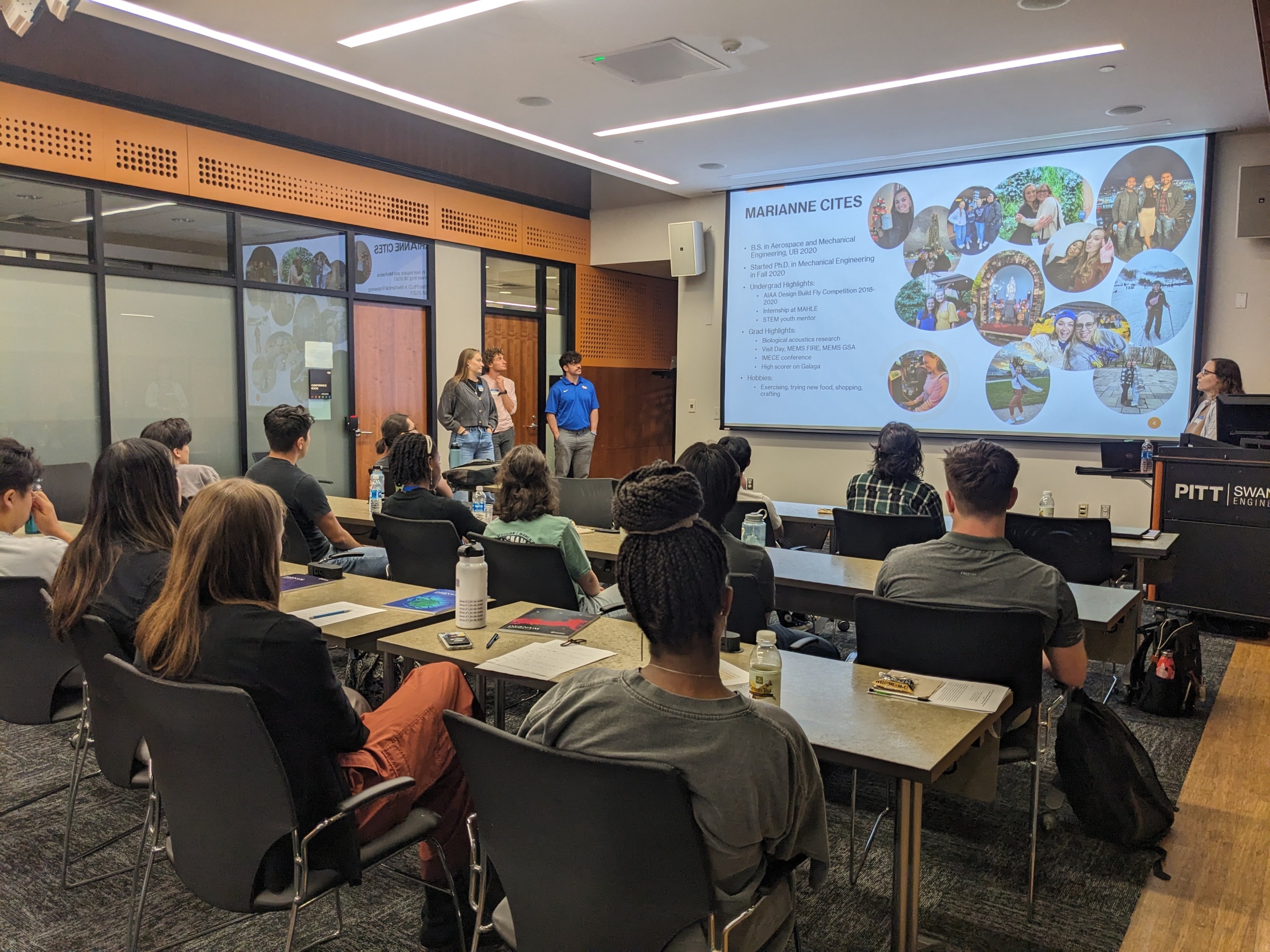 A student presenting with a powerpoint and others watching